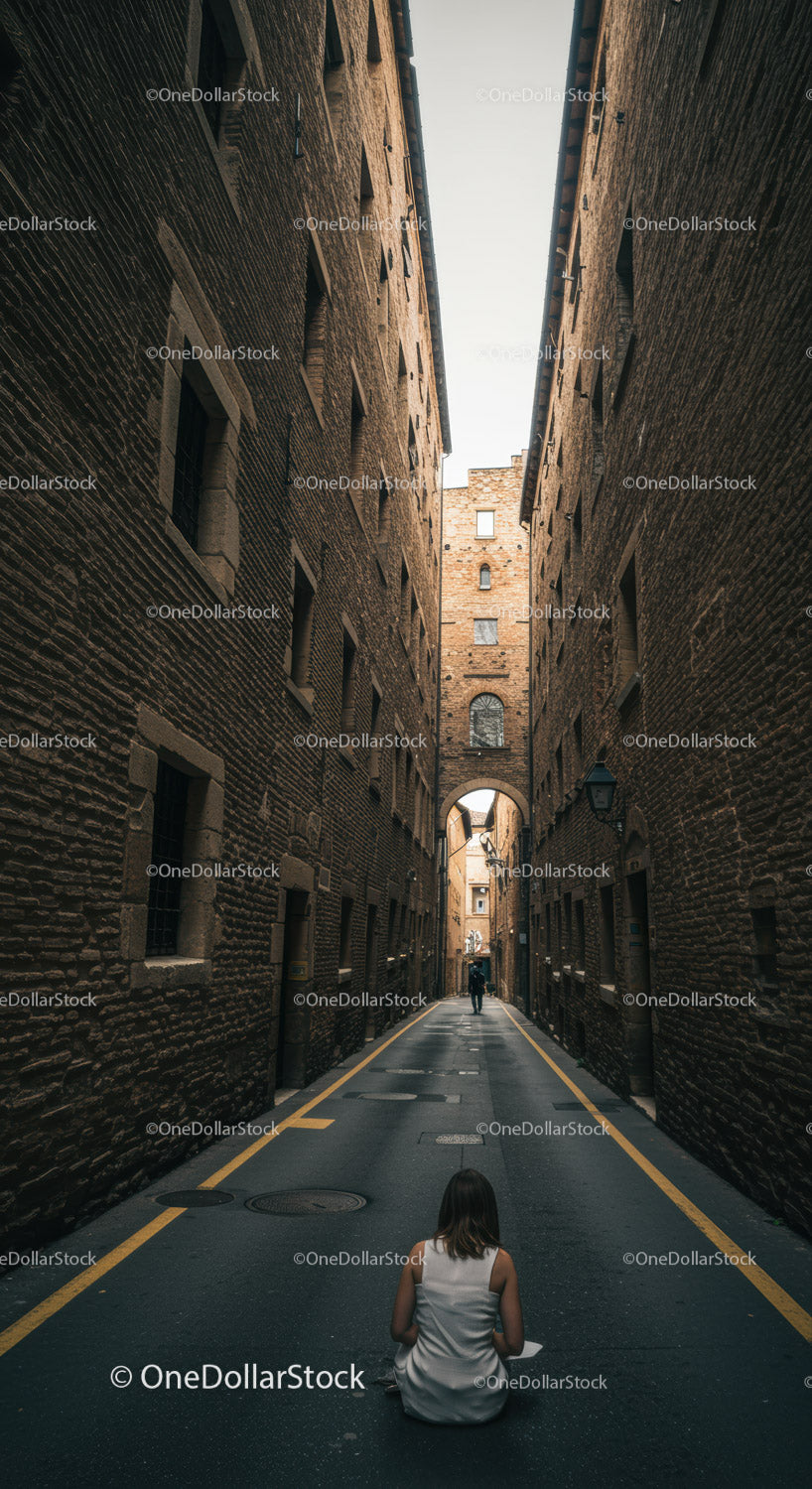 Woman in white dress sitting in narrow urban alleyway