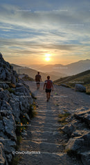 Hikers walking along mountain trail at sunset