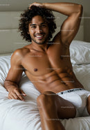 Smiling man relaxing shirtless on white bed