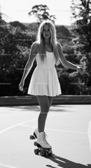 Young woman roller skating outdoors in white dress