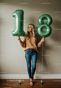 Young woman celebrating 18th birthday with green balloons