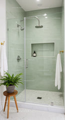 Modern shower enclosure with soft green tiles and plant
