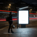 Man walking past illuminated blank billboard at night