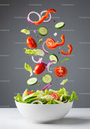 Fresh mixed vegetable salad falling into white bowl