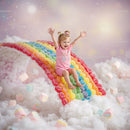 Joyful toddler sliding down colorful candy rainbow
