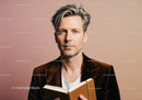Stylish Man with Silver Hair Wearing Brown Velvet Blazer Holding Notebook