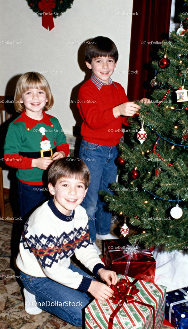 Three kids decorating Christmas tree and unwrapping gifts
