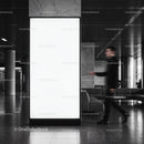 Blurred man walking past large blank indoor billboard