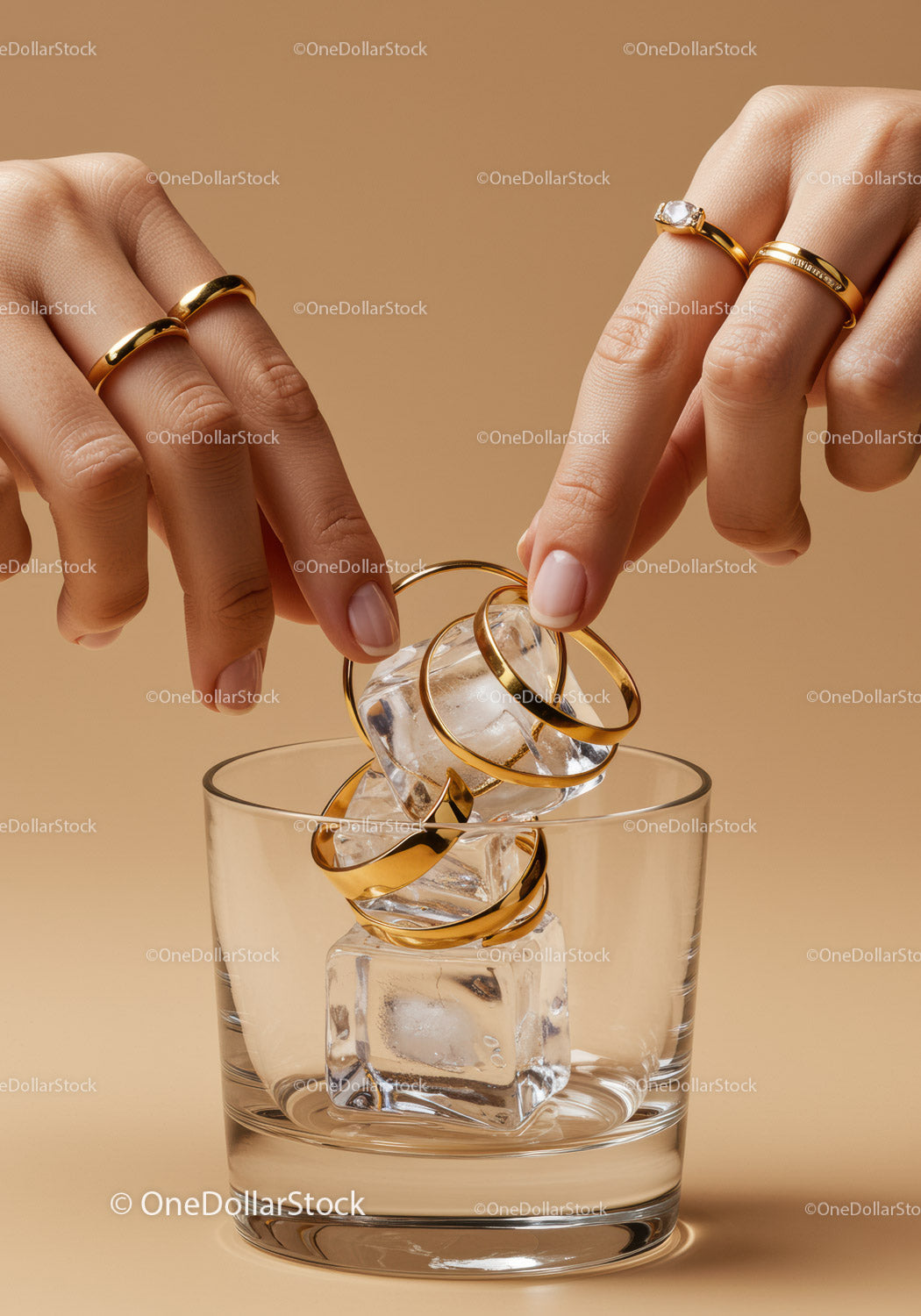Hands Placing Gold Rings on Ice Cubes in Clear Glass