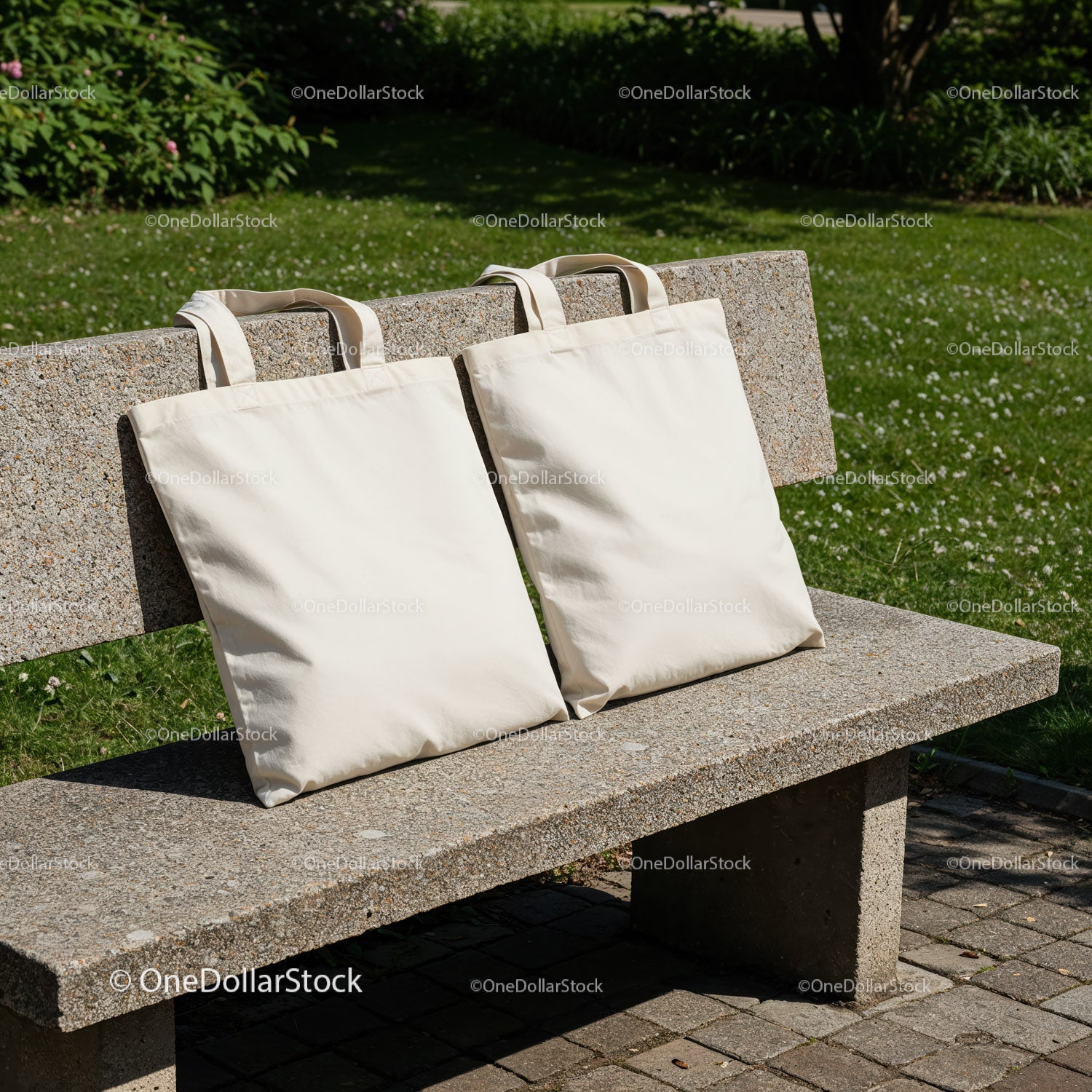 Two blank canvas tote bags on stone bench outdoors