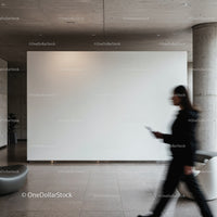 Blurred woman walking past blank modern gallery wall