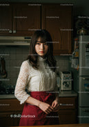 Young Woman in White Lace Blouse and Red Apron in Kitchen