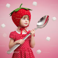 Little girl in strawberry hat holding giant spoon