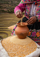 Traditional Andean woman sorting grains in terracotta pot
