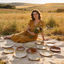 Young woman in mustard dress with handmade pottery outdoors