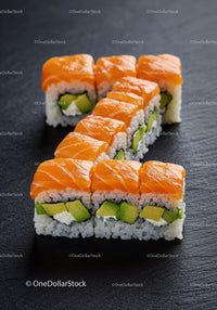 Fresh salmon avocado sushi rolls on black slate