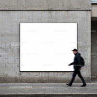 Blurred man walking past large blank billboard on wall