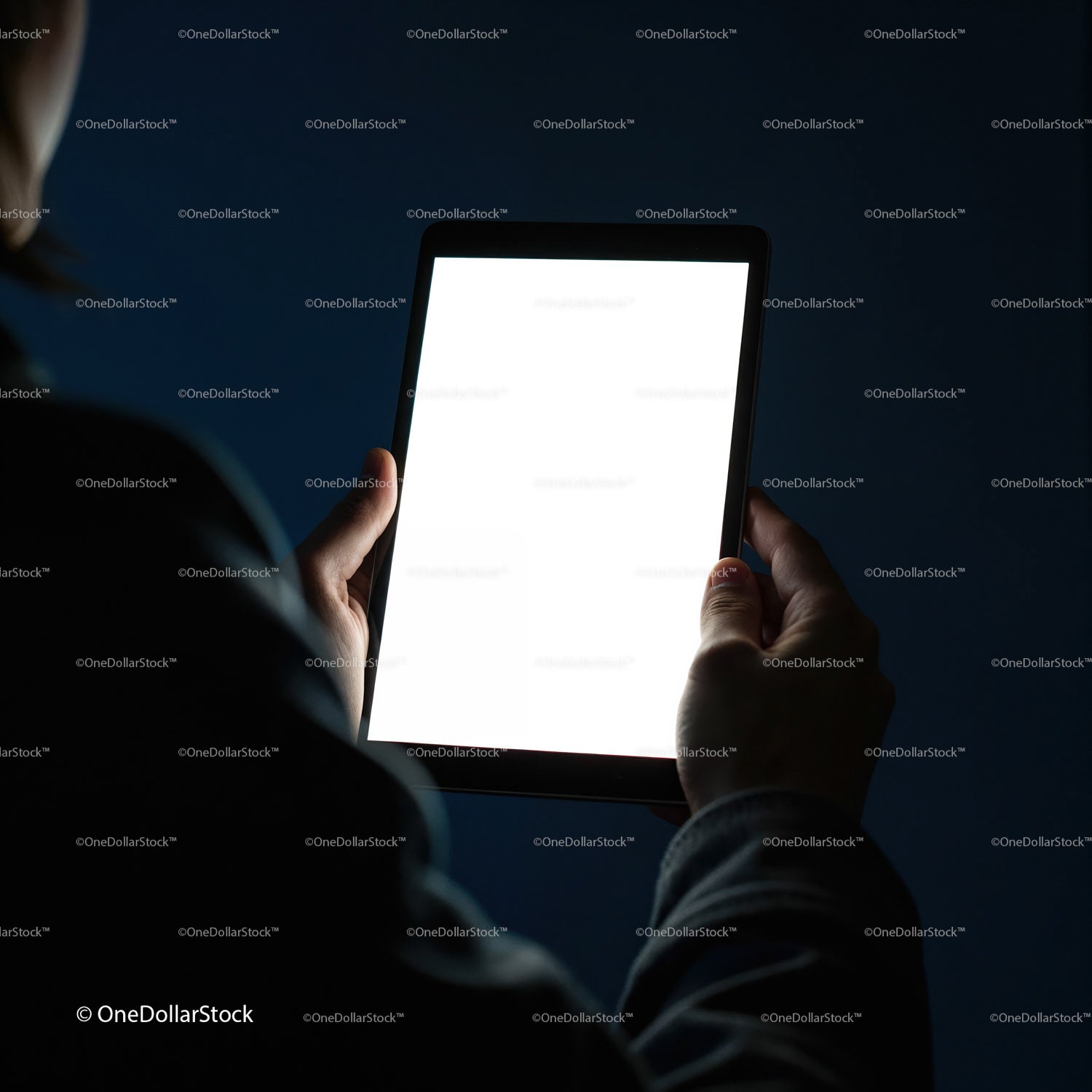 Person holding glowing tablet in dark environment