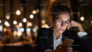 Young Woman in Glasses Using Smartphone at Night with City Lights