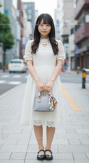 Fashionable Woman in White Lace Dress Holding Handbag on City Street