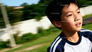 Young boy running outdoors with focused expression