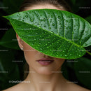 Woman with Large Green Leaf Covering Face Surrounded by Tropical Foliage