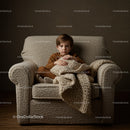 Young boy sitting on cozy armchair with warm blanket