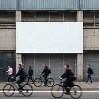 Urban commuters biking and walking past blank billboard