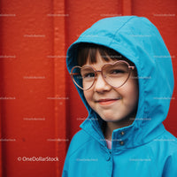 Smiling child in blue raincoat with heart glasses