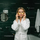 Young Woman Applying Eye Patches in Spa Bathroom