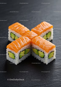 Fresh salmon avocado sushi rolls on black slate
