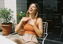 Smiling Woman in Orange Tank Top Relaxing Outdoors in Sunny Garden