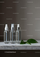 Clear Cosmetic Bottles with Green Leaves on Marble