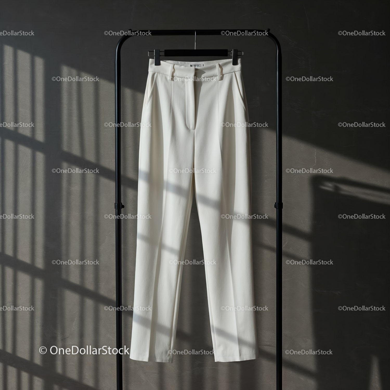 Elegant white tailored trousers hanging on rack
