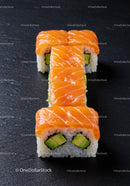 Fresh salmon avocado sushi rolls on black slate