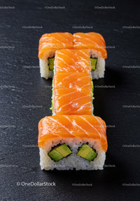 Fresh salmon avocado sushi rolls on black slate