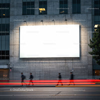 Blurred figures walking past illuminated blank billboard