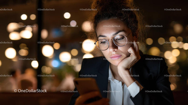Young Woman Using Smartphone in Cozy Coffee Shop at Night