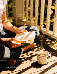Person Reading Book with Hot Coffee on Sunny Porch
