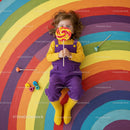 Child playing with colorful lollipop on rainbow floor