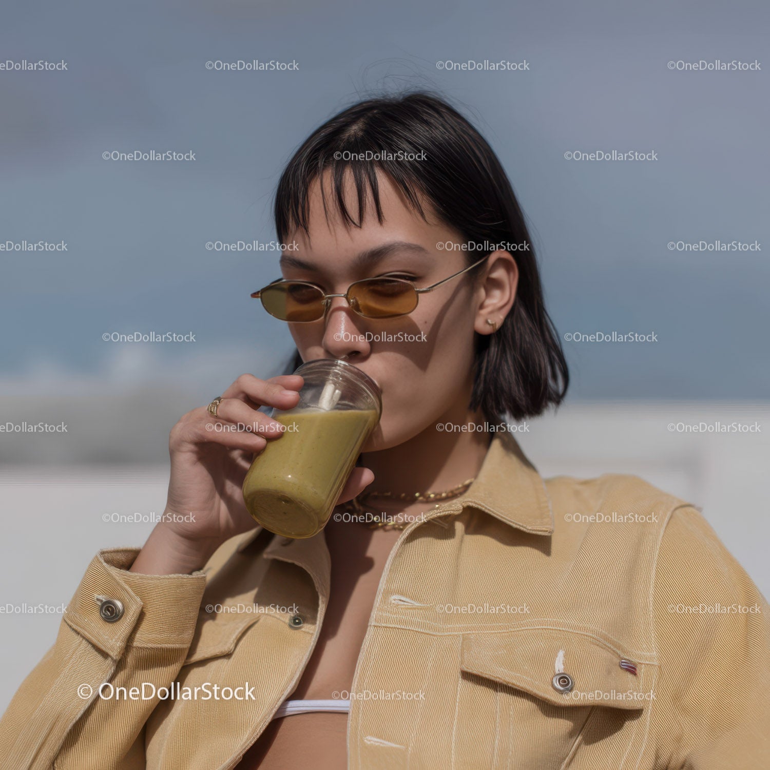 Stylowa kobieta pijąca smoothie na świeżym powietrzu latem