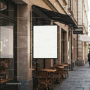 Empty white signboard above cozy outdoor cafe seating