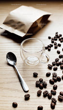 Empty glass coffee cup with spoon and scattered beans