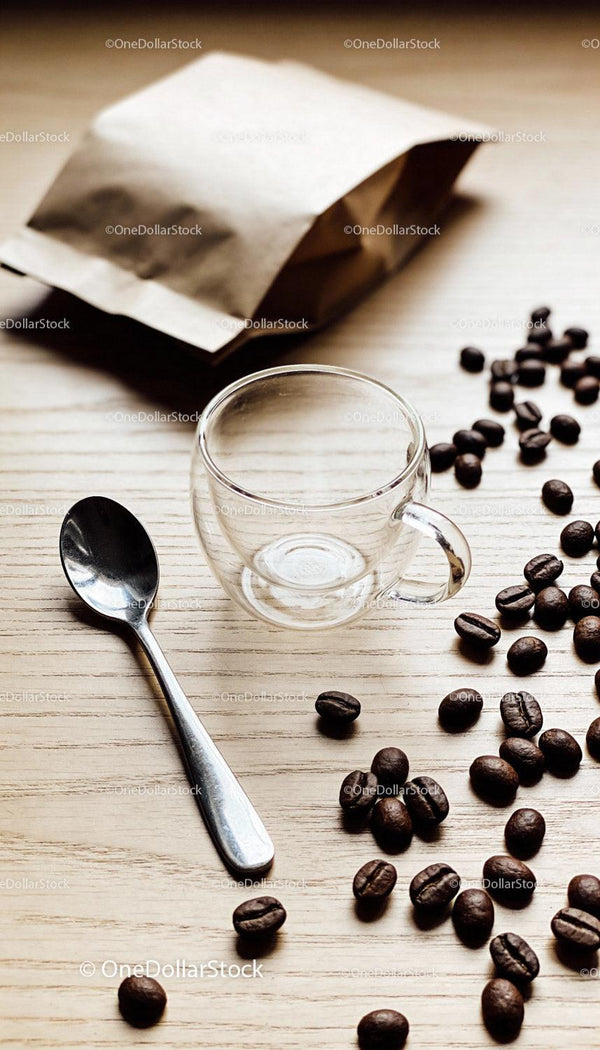 Empty glass coffee cup with spoon and scattered beans