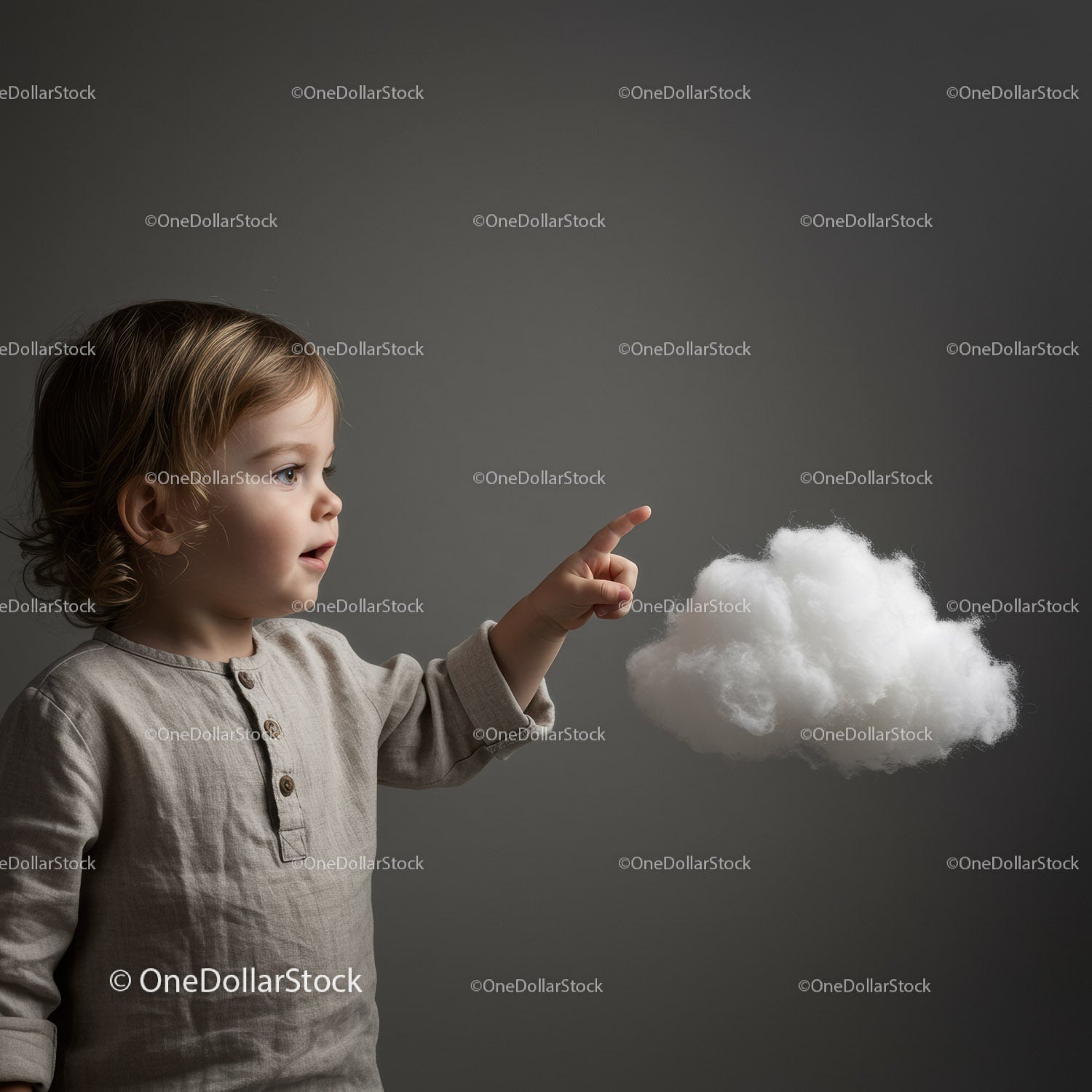 Curious toddler pointing at fluffy white cloud on gray background