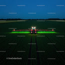 Farm vehicle operating in green fields at night