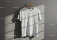 Plain white t-shirt hanging on wooden hanger against wall