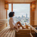 Young Woman Sitting in Sauna with City Skyline View