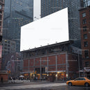 Urban street corner with large blank billboard at dusk