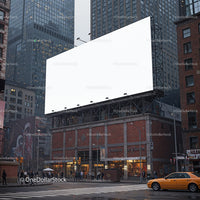Urban street corner with large blank billboard at dusk